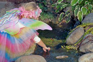 Little girl in fairy costume playing with rock pool