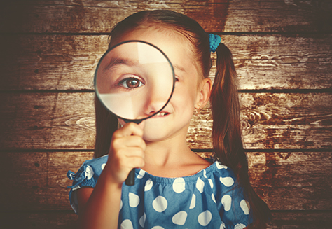 child girl playing with a magnifying glass in the detective
