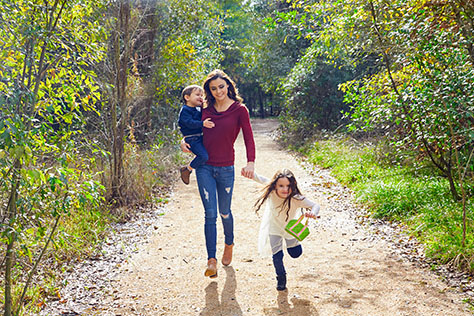 Mother daughter and son family in the park walking in a trail