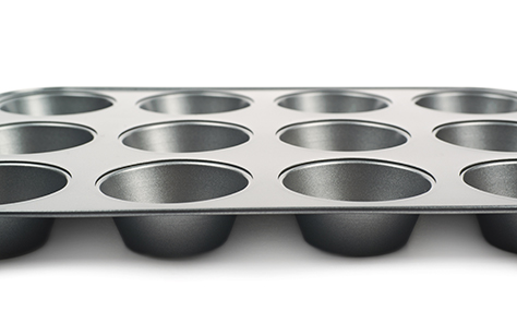 Metal muffin cupcake tray pan isolated over the white background, close-up crop fragment