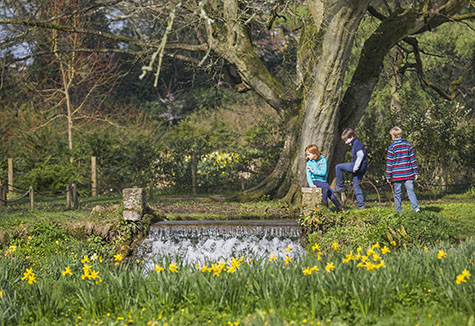 Children playing in the garden in springtime at Mottisfont, Hampshire. Mottisfont is an 18th century house surrounded by a garden paradise.
