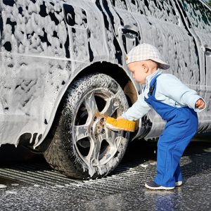 toddler who is washing a car with a sponge